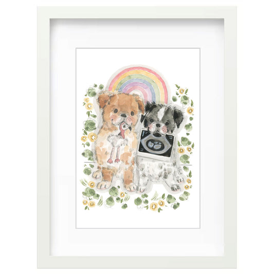 A framed watercolor art print featuring two small dogs sitting together with a rainbow and floral accents, presented in a white frame against a light gray background by sian alexia paine 